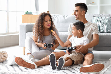 Happy interracial family playing video game and eating chips at home
