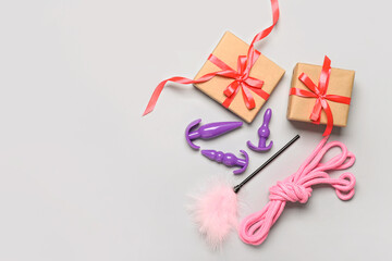 Gift boxes and sex toys on light background