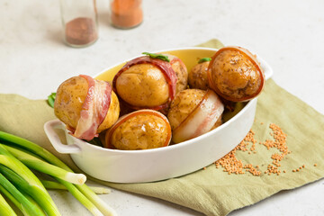 Baking dish of tasty baked potatoes with bacon on white background
