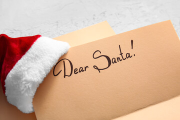 Wish list letter to Santa Claus with text DEAR SANTA and hat on table, closeup