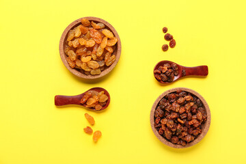 Bowls and spoons with tasty raisins on yellow background
