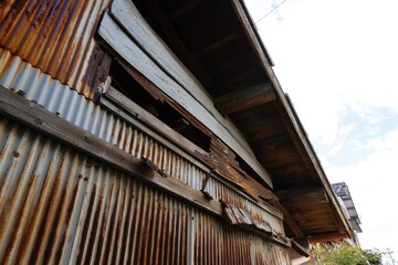 強風と劣化により穴が空いたトタンの壁