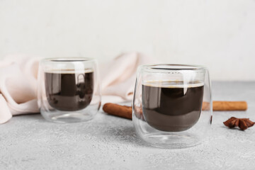 Glasses of tasty coffee with cinnamon on light background