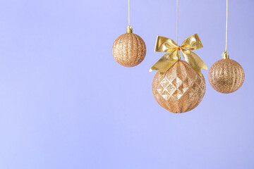 Golden Christmas balls on lilac background, closeup