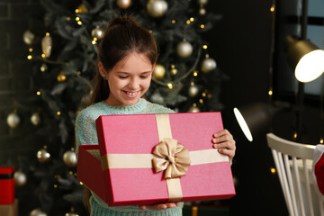 Cute girl opening Christmas gift at home