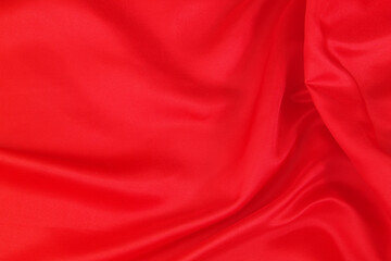Fototapeta na wymiar Red satin or silk fabric backdrop. Beautiful wallpaper, wedding background or design element. 