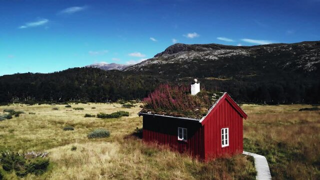 Uprising shot of a small red cabin in the brautiful scandinavian nature