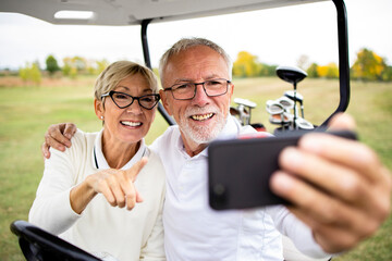 Happy senior couple taking a selfie photo for social networks on the golf course. - Powered by Adobe