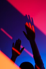 Closeup of silhouette of anonymous woman arm gesturing with open hand over fashion blue, orange and...