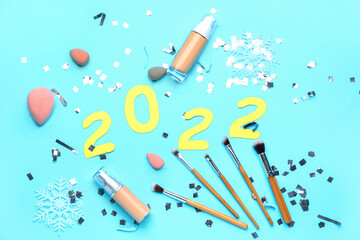 Figure 2022 with makeup supplies and confetti on color background