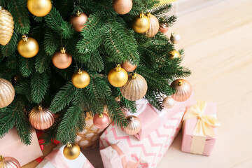 Beautiful Christmas tree with pink gift boxes in room, closeup