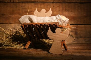 Manger with dummy of baby and paper angels on wooden background. Concept of Christmas story