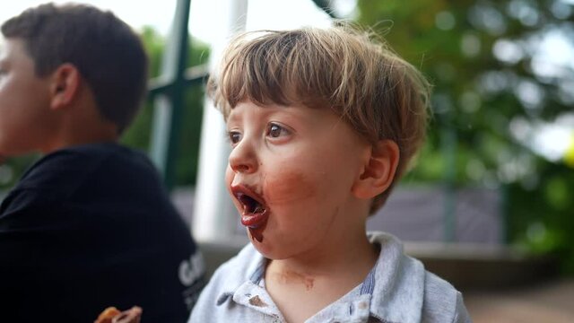 Messy little baby toddler covered with chocolate ice-cream, dirty mouth