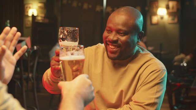 Portrait shot footage of ethnically diverse mature male friends spending great evening in pub drinking beer and having fun