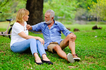 senior woman take care old man That is tired from exercise in park