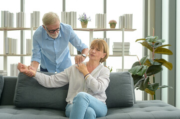 Senior caucasian man doing massage for his wife in living room