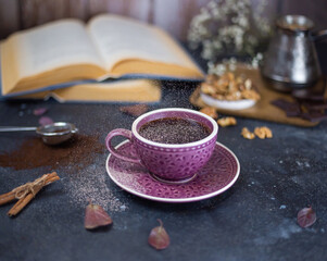 Obraz na płótnie Canvas sprinkle cinnamon powder on hot coffee on a dark wooden background with open books