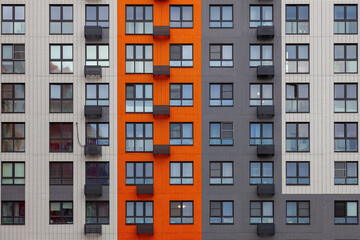 Fototapeta na wymiar Background image - a multi-colored wall of a multi-storey building with windows and balconies