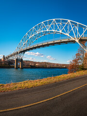 Sagamore Bridge and paved bikeways along the Cape Cod Canal. Peaceful and safe outdoor recreational park in Bourne, Massachusetts. Arching landmark metal bridge connecting Massachusetts mainland to Ca