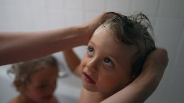 Parent washing child head with shampoo