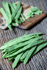 fresh beans on top of an old board, in the background more beans on top of a chopping board
