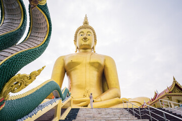 Obraz premium Asian female tourists stand in front Giant Golden Buddha statue at Wat Muang, Ang Thong Province, Thailand.
