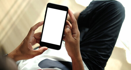 Young man sitting in living room and using smart phone.