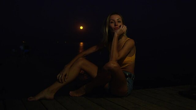 Beautiful Woman Sitting At The Edge Of Wooden Pier In Odessa, Ukraine, - Medium Shot