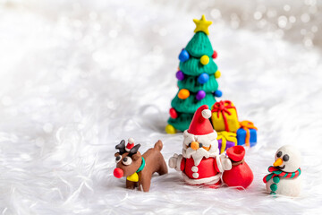 Christmas themed plasticine dolls like Christmas Tree, Santa Claus, Reindeer and Snowman on snow background.