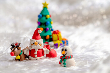 Christmas themed plasticine dolls like Christmas Tree, Santa Claus, Reindeer and Snowman on snow background.