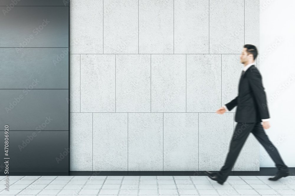 Poster businessman walking in abstract interior with empty mock up place on concrete tile wall and floor. e