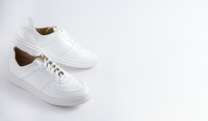 White sneakers isolated on white background. Comfortable, low-travel sports shoes. Unisex casual style. A pair of classic sneakers. All-season leather shoe trend. Sneaker with white laces