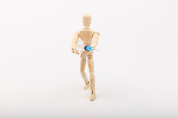wooden mannequin with syringe against white background