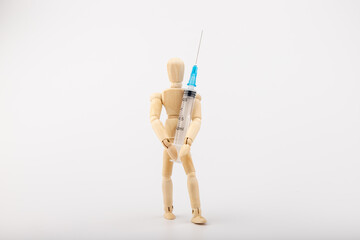 wooden mannequin with syringe against white background