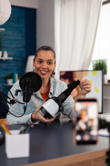 Fototapeta premium Content creator recording review of VR glasses with smartphone. Online podcast of smiling influencer presenting virtual reality goggles. Social media streaming for online recommendation chanel.
