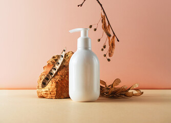 White plastic bottle with pump and brick and natural plant parts creative still life cosmetic photography. Lotion, shampoo, soap, hair conditioner blank empty mockup. Trendy composition