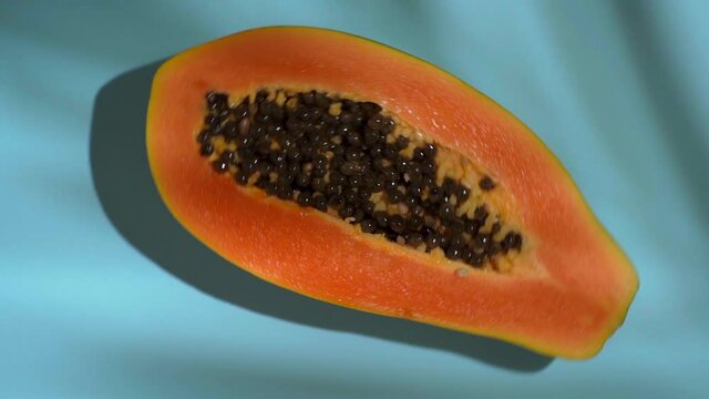 Tropical fruit papaya rotates on a colored sunny background with shadows of a palm tree. Summer, vitamins, food, juice, minimal concept