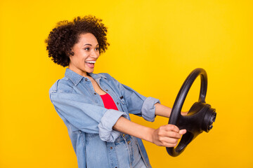 Photo of young happy afro american positive woman look empty space hold wheel isolated on yellow...