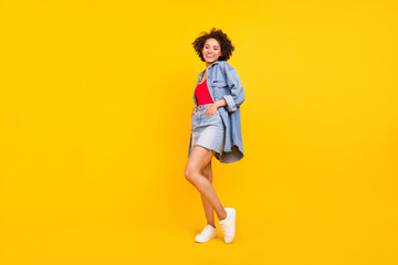 Photo of confident tender girlfriend lady posing wear denim jacket short skirt sneakers isolated yellow color background