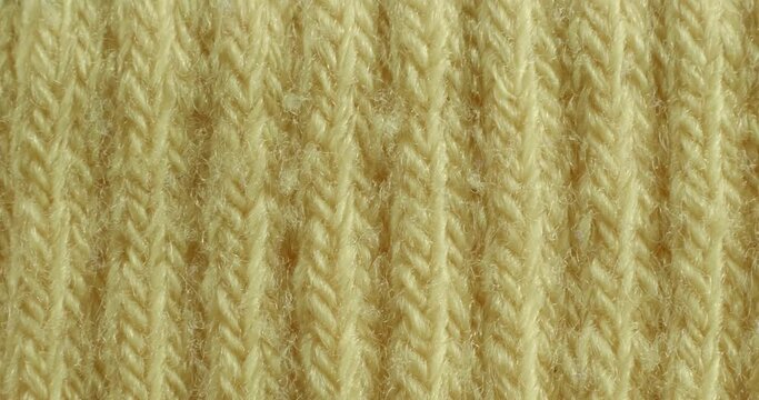 The texture of the knitted product. Macro knitted fragment. Yellow background.