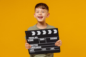 Little small smiling happy boy 6-7 years old wearing green t-shirt holding classic black film making clapperboard isolated on plain yellow background studio Mother's Day love family lifestyle concept. © ViDi Studio