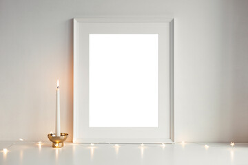 Layout frame with blank copy space for your advertising content, text or greeting, small star shaped garland lights and candle in golden cup against white background. Christmas decoration