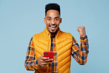 Young black man 20s years old wear yellow waistcoat shirt hold in hand use mobile cell phone doing...