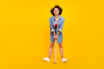 Full body photo of young joyful dark skin woman hold hands bat smile isolated on shine yellow color background