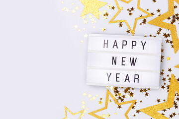 Happy New Year. Lightbox and golden glittering stars confetti on a blue background with copy space.