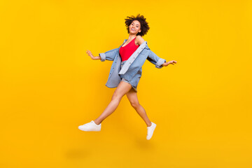 Fototapeta na wymiar Photo of carefree inspired lady jump enjoy flight wear denim jacket mini skirt shoes isolated yellow color background