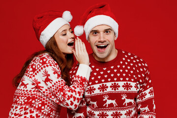 Young couple friends two man woman 20s in sweater hat whispering gossip and tells secret behind her...