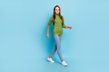 Fototapeta na wymiar Photo of pretty charming young woman wear green turtleneck glasses smiling walking isolated blue color background