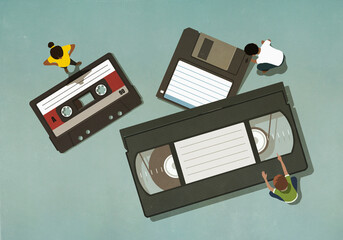 People looking at antiquated cassette and VHS tapes

