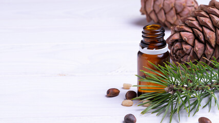 banner, glass bottle with pine cone nuts on white wooden background, natural cosmetics concept